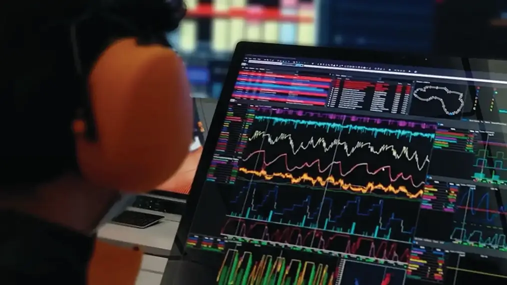 Person viewing a laptop displaying motorsport data analysis software with multiple telemetry graphs, performance charts, and a track map on screen.
