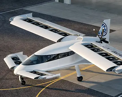 White electric aircraft with multiple rotors mounted along its wings, parked on an airport apron and viewed from above at an angle.